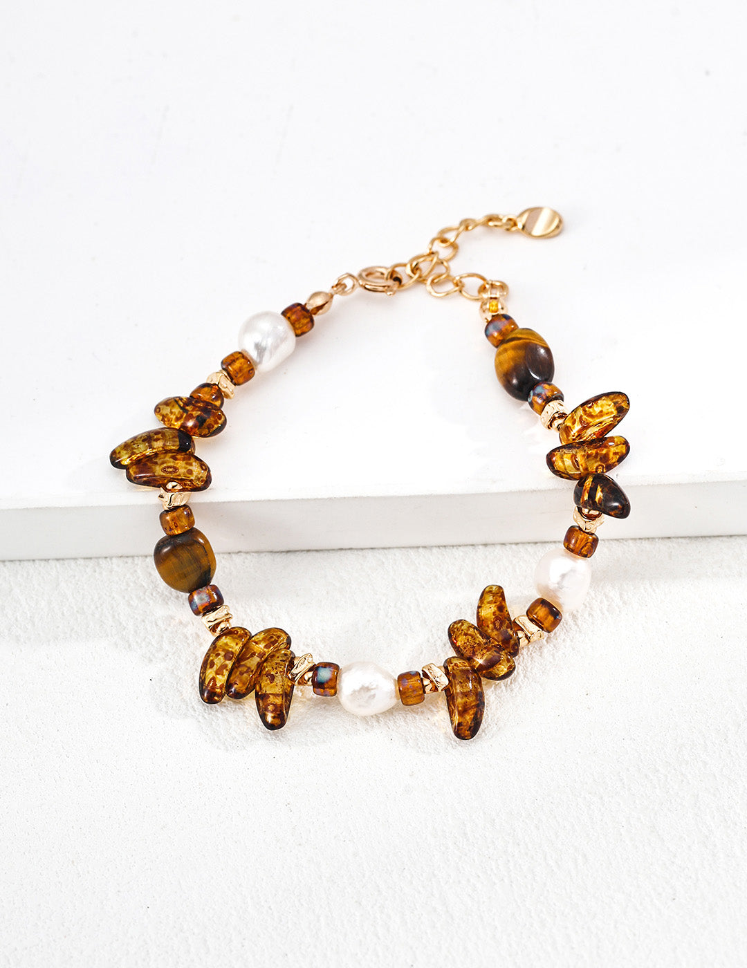 A clean studio shot of the Cybele bracelet, showcasing the eclectic mix of natural pearls, Czech glass, and Tiger's Eye beads on a vintage gold chain.